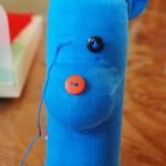 After the nose area is complete, slide the sock onto your water bottle. Use embroidery floss to sew on the nose and eyes and other details you want on the face.