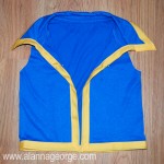 Insert the t-shirt edge into the center of the bias tape. Pin it as you go. The bias tape will go around all the unfinished edges, except the arm holes. Sew on the bias tape.